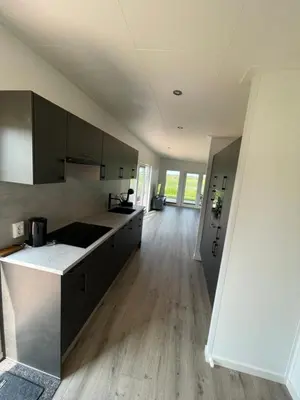 a kitchen with black cabinets and a wooden floor at Miva in Leiderdorp