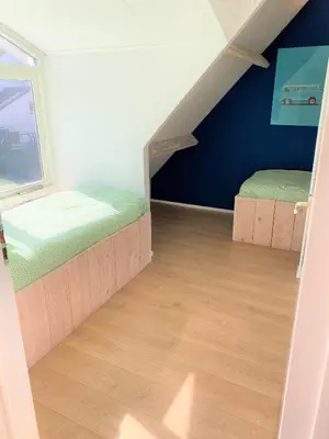 a attic room with two beds and a window at Vakantiehuis Boulevard in Egmond aan Zee