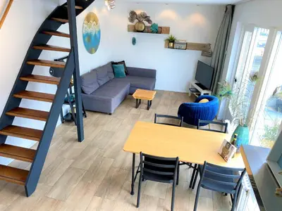 a living room with a staircase and a table and chairs at Vakantiehuis Boulevard in Egmond aan Zee