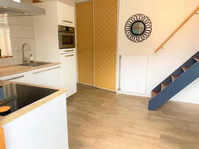 a kitchen with white cabinets and a staircase with a mirror at Vakantiehuis Boulevard in Egmond aan Zee