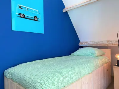 a bedroom with a bed with a picture of a van on the wall at Vakantiehuis Boulevard in Egmond aan Zee