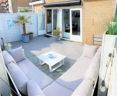 a patio with white furniture and a table at Vakantiehuis Boulevard in Egmond aan Zee