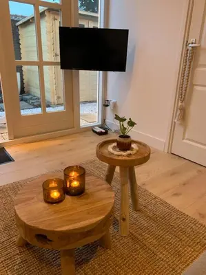a living room with a tv and a table with candles at Faya Beachhouse in Noordwijk aan Zee
