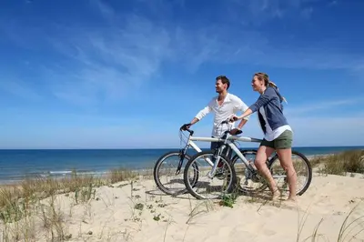 a man and a woman with a bike on the beach at Faya Beachhouse in Noordwijk aan Zee
