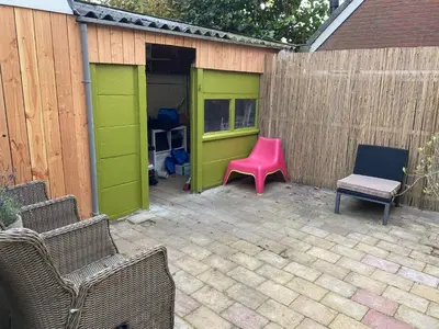 a patio with a pink chair and a fence at Spes Salutis in Badhoevedorp