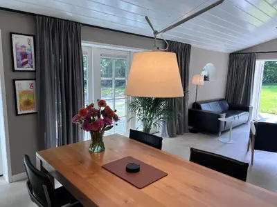 a dining room table with a vase of flowers on it at Het Zomerhuis in Zuidbakkum