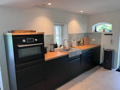a kitchen with a black stove and a sink at Het Zomerhuis in Zuidbakkum