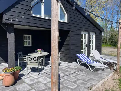 a black shed with a table and chairs on a patio at Het Zomerhuis in Zuidbakkum