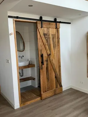 a sliding barn door in a bathroom with a sink at Naast 37 Overnachten in Driebergen