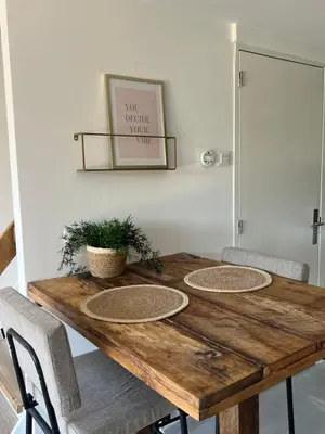 a wooden table with three chairs and a picture on the wall at Naast 37 Overnachten in Driebergen