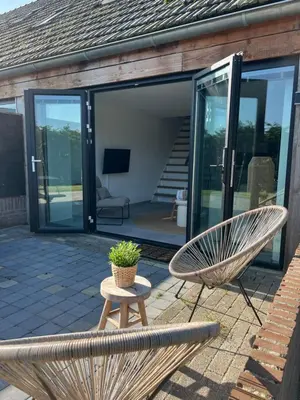 a patio with two chairs and a bench and a table at Naast 37 Overnachten in Driebergen