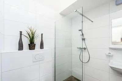 a white bathroom with a shower and a sink at Plantage Garden Apartments in Amsterdam