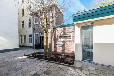a tree in a courtyard in front of a building at Plantage Garden Apartments in Amsterdam