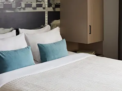 a bed with blue and white pillows and a cabinet at YAYS Amsterdam Maritime by Numa in Amsterdam