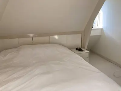 a white bed in a white room with a window at Villa Bollenstreek in Hillegom