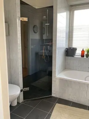 a bathroom with a shower and a tub and a toilet at Villa Bollenstreek in Hillegom