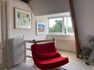 a red chair in a room with a window at Villa Bollenstreek in Hillegom