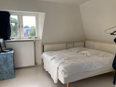 a white bed in a room with a window at Villa Bollenstreek in Hillegom