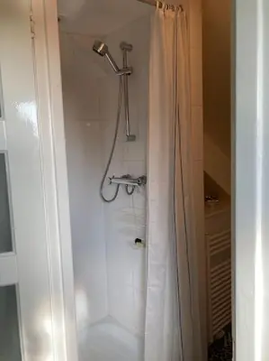 a shower with a white shower curtain in a bathroom at Villa Bollenstreek in Hillegom