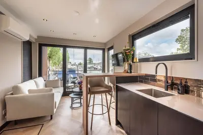 a kitchen with a sink and a living room at Luxury Watervilla Near Amsterdam And Schiphol in Aalsmeer
