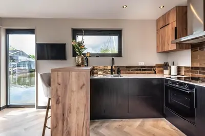 a kitchen with black appliances and wooden cabinets at Luxury Watervilla Near Amsterdam And Schiphol in Aalsmeer