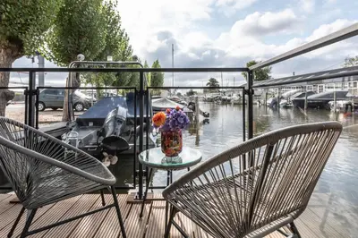 a balcony with two chairs and a table with a vase of flowers at Luxury Watervilla Near Amsterdam And Schiphol in Aalsmeer