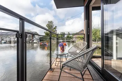 a balcony with a table and chairs and water at Luxury Watervilla Near Amsterdam And Schiphol in Aalsmeer