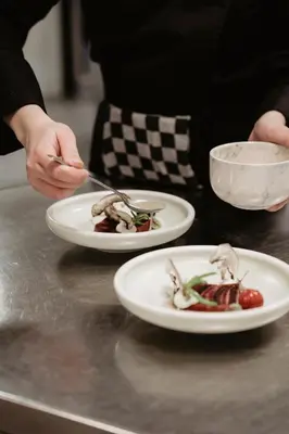 a person holding a knife and fork with two plates of food at Leerhotel Het Klooster in Amersfoort