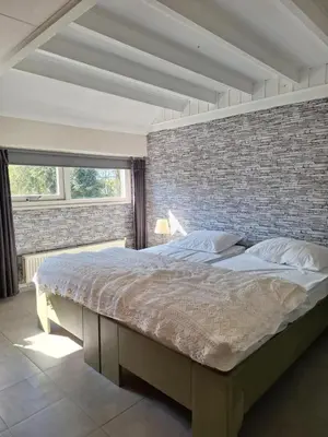 a large bed in a bedroom with a brick wall at Rekerlanden 46 in Warmenhuizen