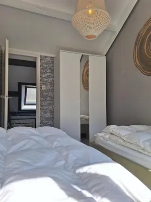 a bedroom with a large white bed and a chandelier at Rekerlanden 46 in Warmenhuizen