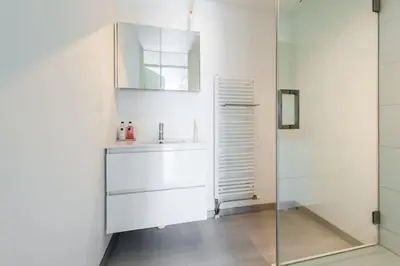 a white bathroom with a sink and a mirror at Schitterend appartement, 150 m van het strand in Katwijk aan Zee