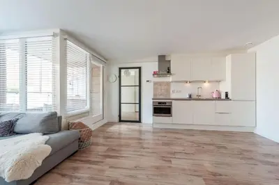a living room with a couch and a kitchen at Schitterend appartement, 150 m van het strand in Katwijk aan Zee