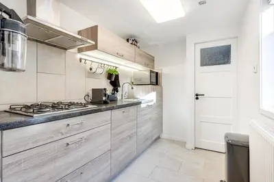 a kitchen with wooden cabinets and a stove top oven at Dorpsgeluk centrum Uitgeest in Uitgeest
