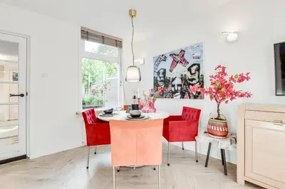 a dining room with a table and red chairs at Dorpsgeluk centrum Uitgeest in Uitgeest