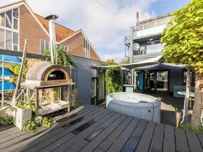 an outdoor deck with a hot tub and a building at De Kaag Watersport Groepsaccommodatie - 80 pers in Kaag