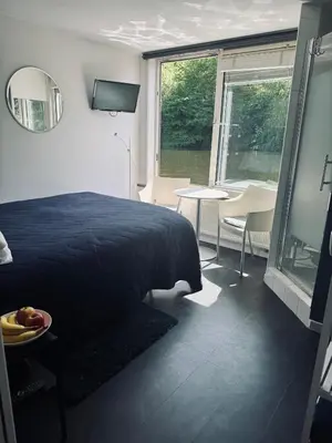 a bedroom with a bed and a table and a window at Peaceful room on a houseboat in the city centre in Amsterdam