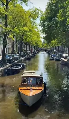 a small boat in a canal with cars parked at Décor Canal House in Amsterdam