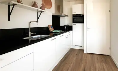 a kitchen with white cabinets and a sink at Havenzicht by Droomvilla in Uitgeest