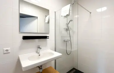 a white bathroom with a sink and a shower at Havenzicht by Droomvilla in Uitgeest