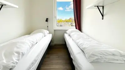 two white beds in a room with a window at Havenzicht by Droomvilla in Uitgeest