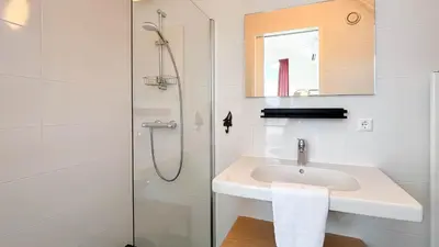 a white bathroom with a sink and a shower at Havenzicht by Droomvilla in Uitgeest