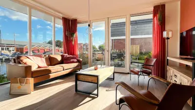 a living room with a couch and large windows at Havenzicht by Droomvilla in Uitgeest