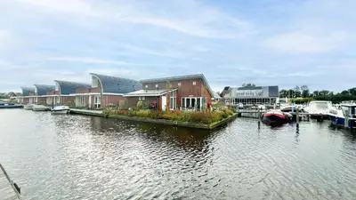 a marina with houses and boats on the water at Droomzicht by Droomvilla in Uitgeest