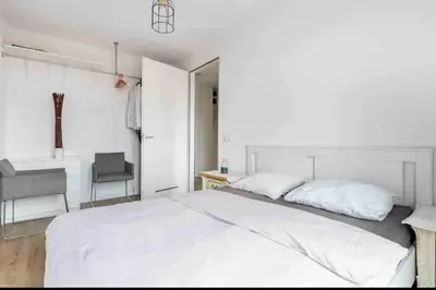 a bedroom with a large white bed and a chair at 120m2 Spacious 4-bedroom Apartment with Roofterras in Amsterdam