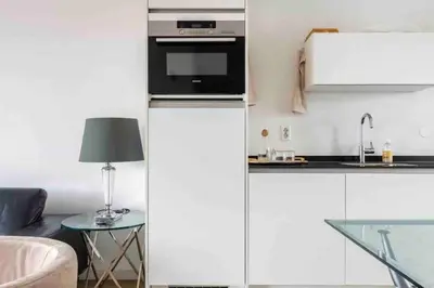 a kitchen with white cabinets and a stove top oven at 120m2 Spacious 4-bedroom Apartment with Roofterras in Amsterdam