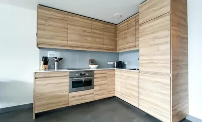 a kitchen with wooden cabinets and a stove at Schelpzicht by Droomvilla in Uitgeest