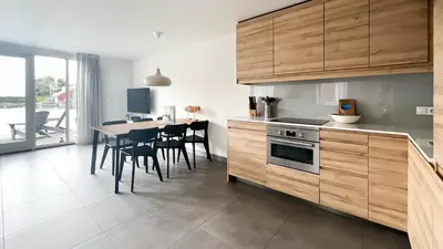 a kitchen with wooden cabinets and a table with chairs at Schelpzicht by Droomvilla in Uitgeest