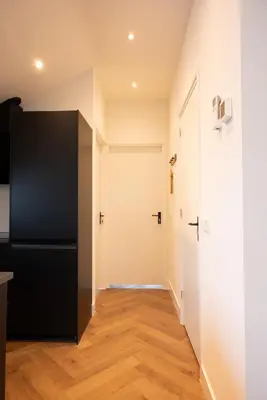 a hallway with a black refrigerator and a door at PURMERENT Apartments in Purmerend