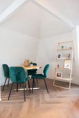 a dining room with a table and green chairs at PURMERENT Apartments in Purmerend