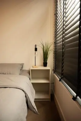 a bedroom with a bed and a window with blinds at PURMERENT Apartments in Purmerend